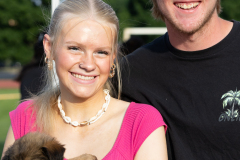 two people smiling with a puppy