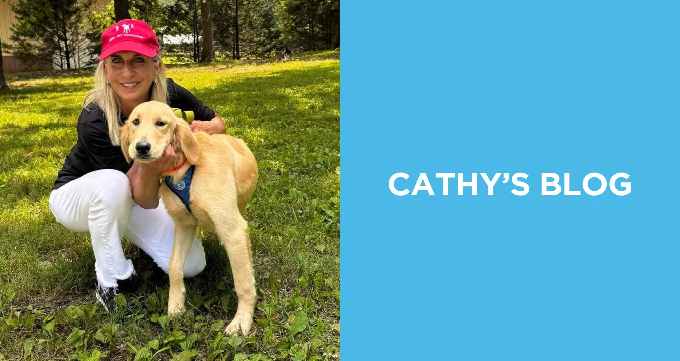 Cathy Bissell poses with a golden retriever puppy.